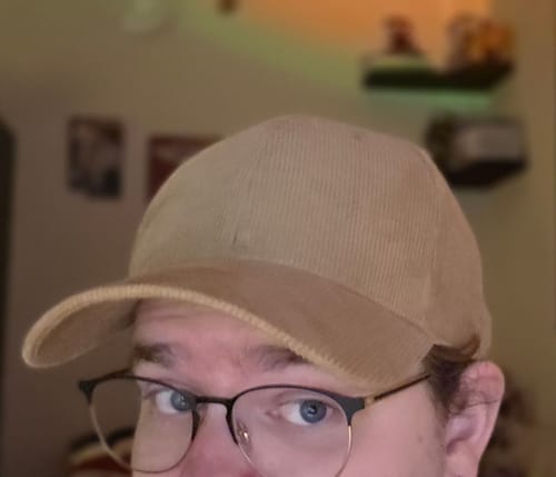 Close-up of a reviewer wearing the tan corduroy baseball cap, showing its fit and texture.