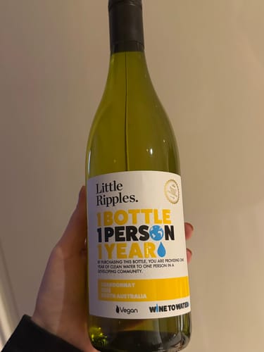 A customer holding a bottle of the Chardonnay, showing the front label.