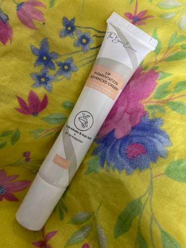 Customer's Lip Pigmentation Advanced Cream tube shown on a yellow floral background.