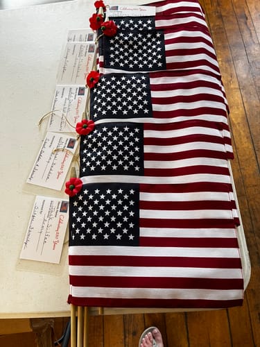 Reviewer's American Stick Flags laid out for a veterans project with poppies attached.