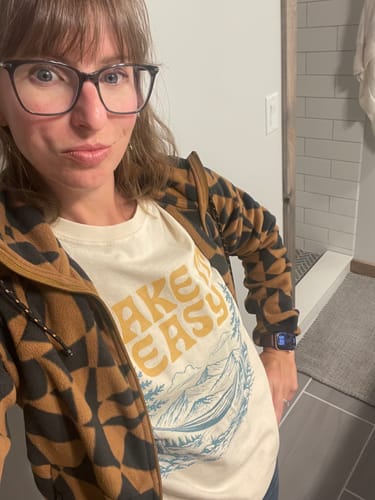 Reviewer wearing the cream Take It Easy T-Shirt, showing its relaxed fit under an open patterned jacket.