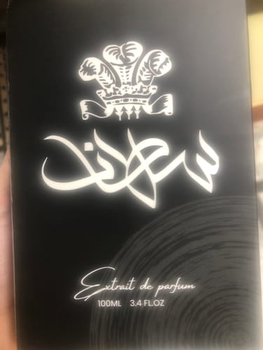 Customer shows the black box for Sultan perfume, with the name in white Arabic calligraphy and a crest above it.