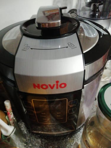 Un client prezintă multicookerul său argintiu Novio SteelCook pe un blat de bucătărie.