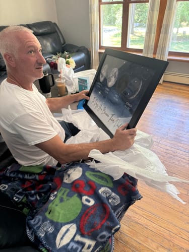 Reviewer's husband smiling while holding the framed personalized Starry Night poster.