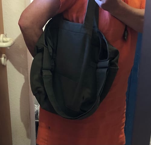 Customer wearing the dark green canvas shoulder bag over their shoulder.