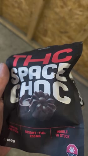 Ein Kunde hält die schwarze Verpackung der THC SpaceChoc Schokolade in der Hand.