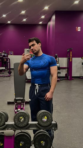 Reviewer at the gym wearing the blue, super fitted Superman Compression Tee.