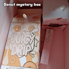 Reviewer unboxing their Mystery Donut Box, revealing the Juicy Drip lip duo and other surprise products.