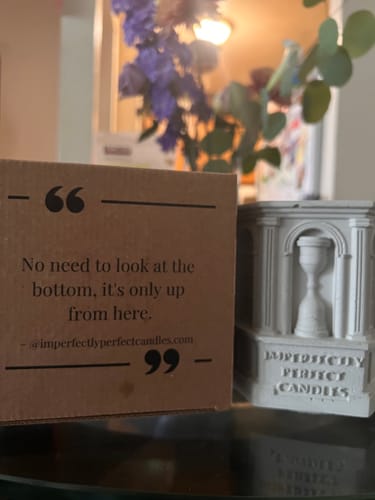 Reviewer's grey, cement Monument candle vessel sitting on a table next to its packaging.
