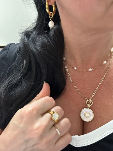 Reviewer wearing a layered set from the WaterProof Jewelry Bundle, including gold necklaces, rings, and pearl-drop earrings.