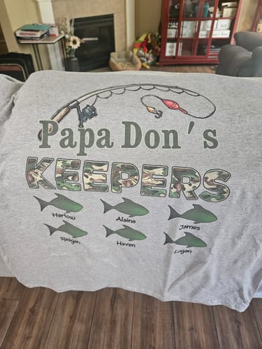 Customer's personalized grey fishing shirt with "Papa Don's KEEPERS" design and six fish printed with grandkids' names.