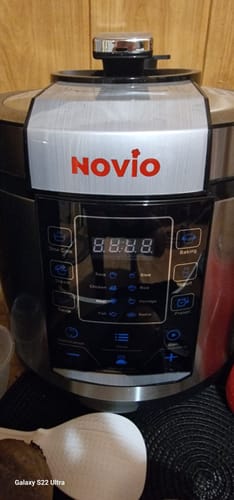 Prim-plan de la un client cu friteuza Air Fryer Novio StonePro, arătând panoul de control negru și logo-ul roșu.