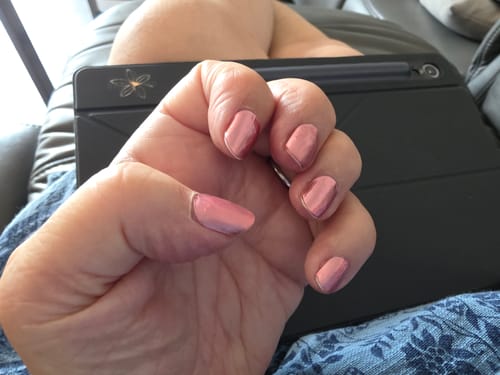 Die Hand einer Kundin mit den 'Rosé Chrome' UV-Nagelfolien, die in einem hellen, kupferfarbenen Ton schimmern.