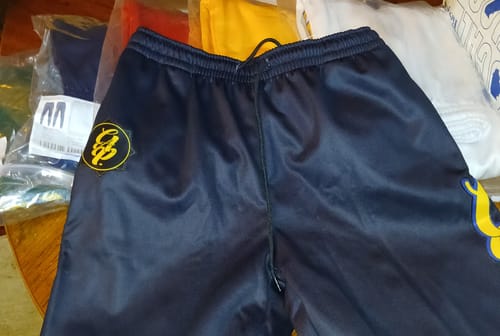 A customer's custom black sweatpants with a yellow and black stitched logo on the upper thigh.