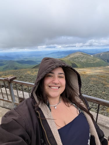 Reviewer smiling while wearing the Sarya Snake Chain Silver Necklace with a hooded jacket outdoors.