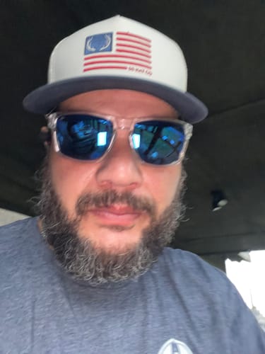 Customer wearing a white and navy trucker hat from the Hat of the Month Crew with a flag logo.