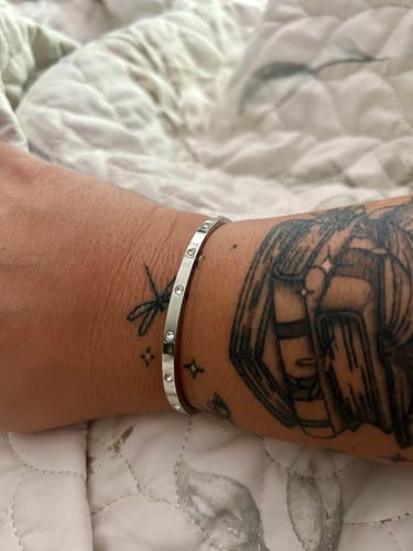 Customer wearing the silver-toned Vina Bracelet with inset stones on their tattooed wrist.