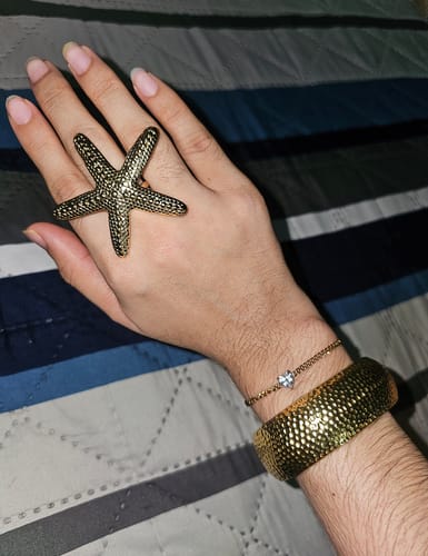Cliente mostrando el Anillo Ajustable Starfish dorado en su mano.