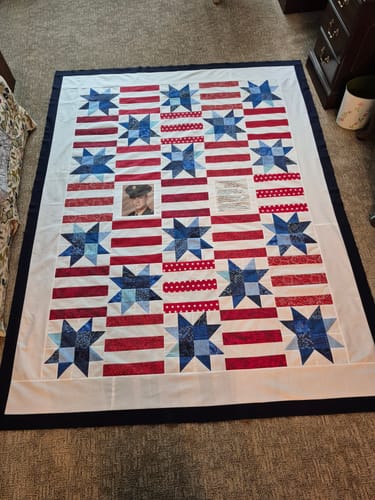 Customer's finished Red, White, and Cute Quilt of Valor, with custom photo and text blocks, laid out on a floor.