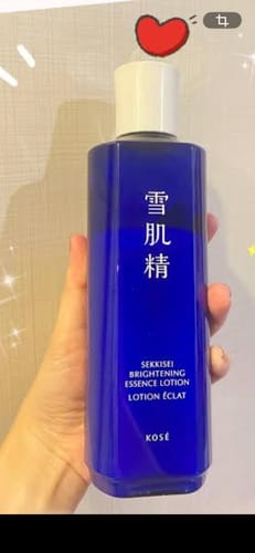 Reviewer holding the vibrant blue bottle of Kose Sekkisei Brightening Essence Lotion.