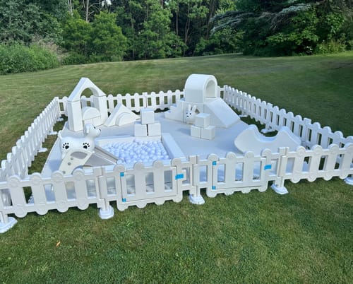 Customer's white Soft Play - Fun Arena with a ball pit and fence, fully assembled on a lawn.