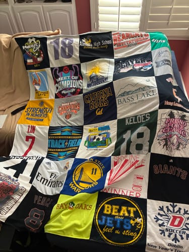 Customer's colorful Project Repat T-Shirt Quilt, made from many different shirts, draped over a couch.