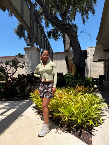 Reviewer standing outdoors wearing the patterned W154 Paradise Shorts with a light green jacket.