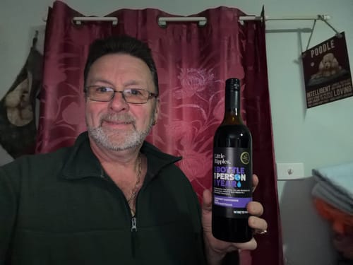 Reviewer smiling and holding up a bottle of the Cabernet Sauvignon.