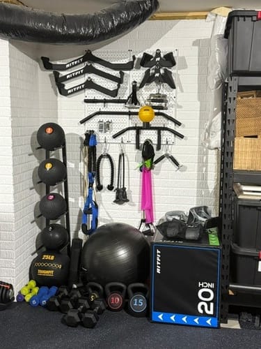 Customer's home gym with several pairs of black RitFit Rubber Hex Dumbbells organized on the floor.