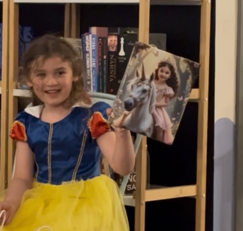 Customer's child in a princess costume holding their Enchanted Unicorn Princess canvas print.