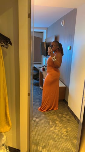 Reviewer's side profile in the form-fitting orange Modal Open Back Dome Maxi Dress.