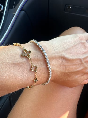 Ein Kunde trägt das goldene Prestige Clover Armband am Handgelenk neben einem anderen Armband.