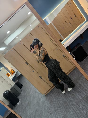 Customer takes a mirror selfie in a locker room wearing the long, baggy Hunting Season Cargo Joggers.