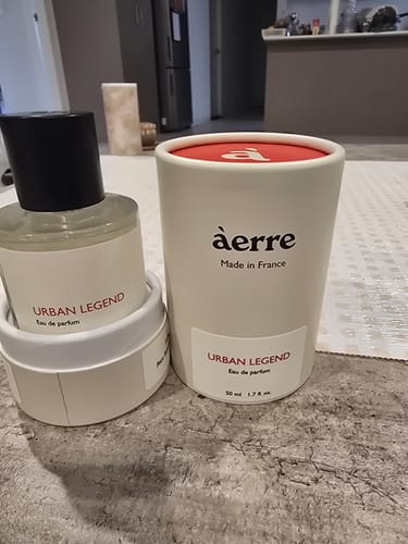 Customer's Urban Legend perfume bottle shown next to its elegant white cylindrical packaging on a tabletop.