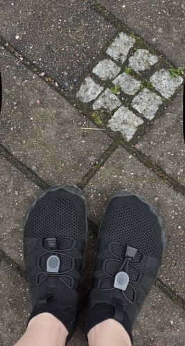 Arvostelijan mustat Vapauta Varpaat™ -paljasjalkakengät jalassa kivetyksellä.