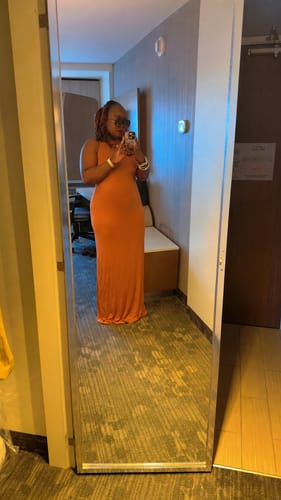 Reviewer taking a mirror selfie in a long, orange Modal Open Back Dome Maxi Dress.
