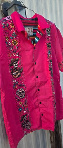 Customer's bright pink El Reventón Fiesta Guayabera on a hanger, showing the detailed calavera print.