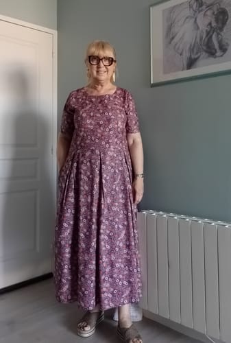 Cliente portant la Robe Louisa à fleurs d'aubergine, montrant sa coupe ample et ses poches pratiques.
