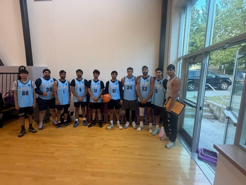 Reviewer's basketball team posing in their light blue and black custom jerseys on a court.
