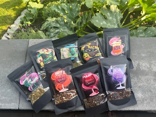 Kundenbewertung: Alle acht Sorten des Cold Brew Tee Bundles mit bunten Etiketten sind auf einer Steinmauer im Freien arrangiert.
