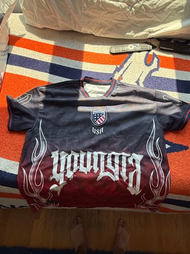 Customer's International Football Jersey laid flat, showing the front with the "YoungLA" flame graphic and USA crest.