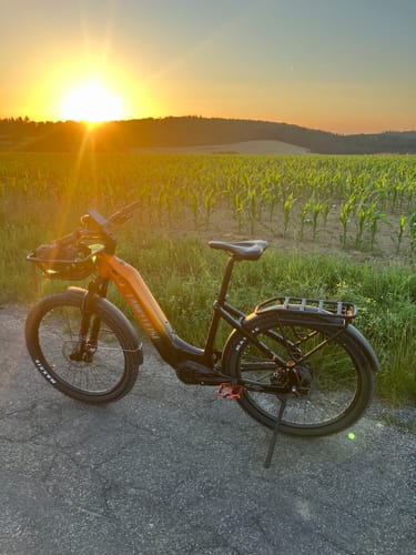 Customer's Lankeleisi MG600 Lite bike on a country road with a cornfield in the background at sunset.