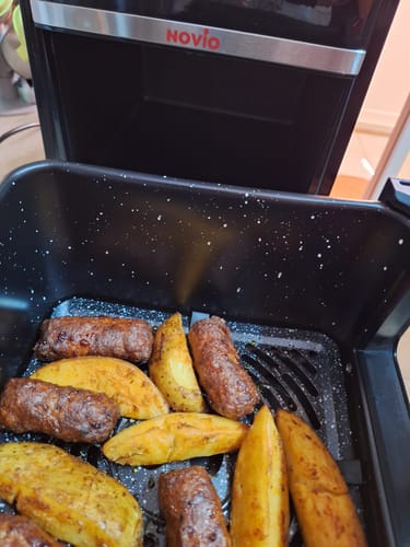 Client arătând mici și cartofi noi rumeniți în cuva friteuzei Air Fryer Novio StonePro.