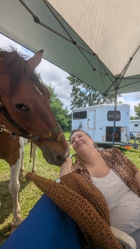Reviewer wearing the sheer leopard print top layered over a white shirt while interacting with a horse.