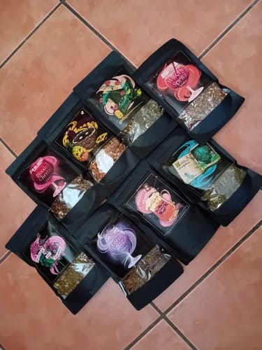 Ein Kunde zeigt die acht verschiedenen Teebeutel aus dem Cold Brew Tee Bundle auf einem Fliesenboden.