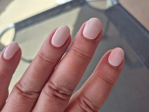 Nahaufnahme der Hand einer Kundin mit den hellrosa UV-Gelfolien „Blush Aurora“.