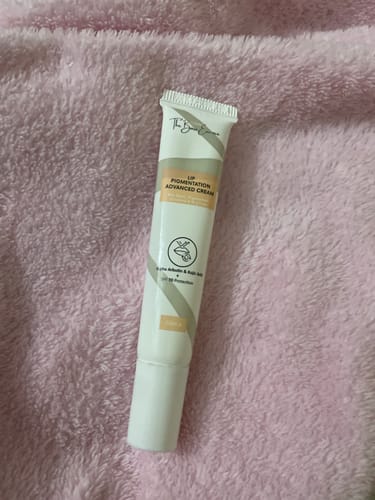 Customer's Advance Lip Pigmentation Cream tube lying on a fluffy, pink surface.