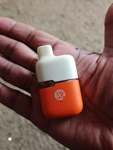 Customer holding the compact orange and white 1ML THCA VAPE in their palm.