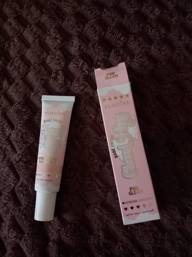 Customer's Babe Im On Cloud Nine Strobe Cream tube and box in the shade Pink Gleam, on a dark textured surface.