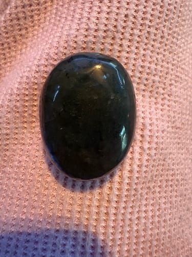Customer's dark, polished crystal from the VIP Crystal Club resting on a pink cloth.